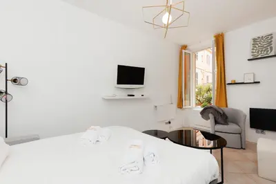 a white bedroom with a bed and a tv at Immogroom - Suquet - Vieux Port - Charmant T2 in Cannes