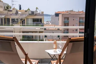 a balcony with two chairs and a table with wine glasses at Évasion Pointe Croisette, vue mer, plage à une minute in Cannes