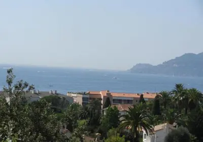 a view of the ocean with buildings and palm trees at Villa Livia - Citea - Groupe Pierre & Vacances Tourisme Piscine et mer à proximité - Résidence rénovée in Cannes