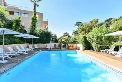 a swimming pool with white chairs and umbrellas at Villa Livia - Citea - Groupe Pierre & Vacances Tourisme Piscine et mer à proximité - Résidence rénovée in Cannes