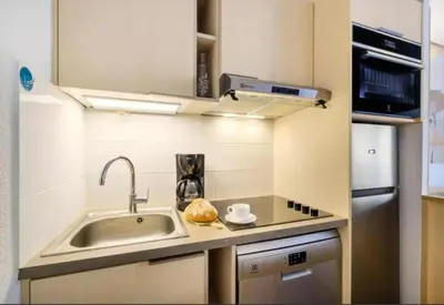 a small kitchen with a sink and a refrigerator at Villa Livia - Citea - Groupe Pierre & Vacances Tourisme Piscine et mer à proximité - Résidence rénovée in Cannes