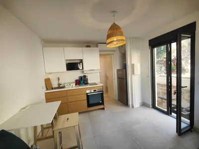 a kitchen with white cabinets and a large window at studio la mimosette in Cannes