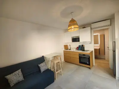 a living room with a blue couch and a kitchen at studio la mimosette in Cannes