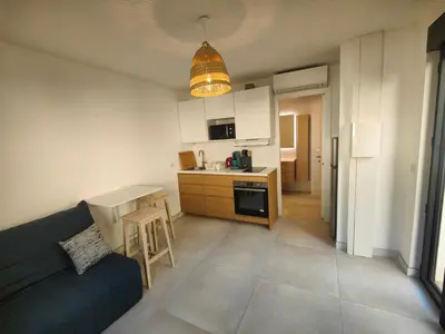 a living room with a couch and a kitchen at studio la mimosette in Cannes