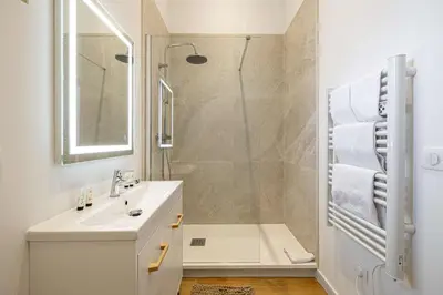 a white bathroom with a shower and a sink at LE COSY un havre de paix près de la Croisette in Cannes