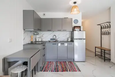 a kitchen with a white refrigerator and a table at Studio dans résidence neuve - Terrasse et jardin in Cannes