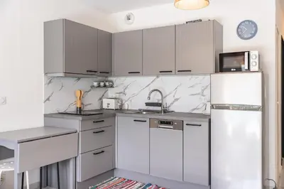 a kitchen with white cabinets and a refrigerator at Studio dans résidence neuve - Terrasse et jardin in Cannes