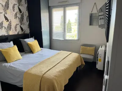a bedroom with a bed with yellow pillows and a window at Apartment in park with pool in Cannes