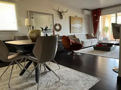 a living room with a table and chairs at Apartment in park with pool in Cannes