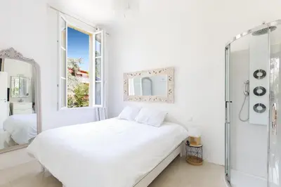 a white bedroom with a bed and a mirror at Palais Beaulieu Magnifique 3p 2 chambres in Cannes