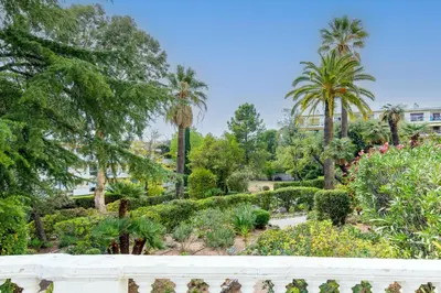 a view of a garden with palm trees and bushes at Palais Beaulieu Magnifique 3p 2 chambres in Cannes