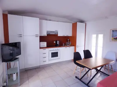 a kitchen with white cabinets and a table with chairs at Villa Divona - central gem with sunset balcony & pool in Cannes