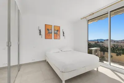 a white bedroom with a bed and large windows at REF 1996 Cannes Croisette - Sea view apartment for rent in Cannes
