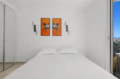 a white bedroom with a bed with four pictures on the wall at REF 1996 Cannes Croisette - Sea view apartment for rent in Cannes