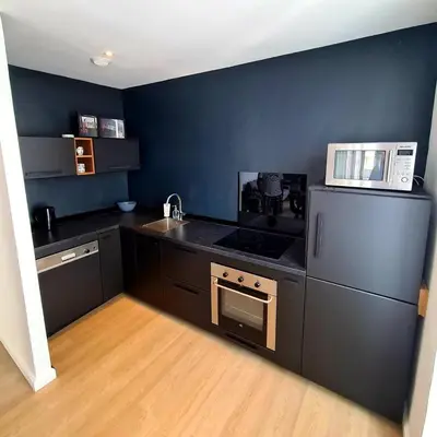 a kitchen with black counters and a white microwave at 2 Bedrooms 5 min walk to Croisette in Cannes