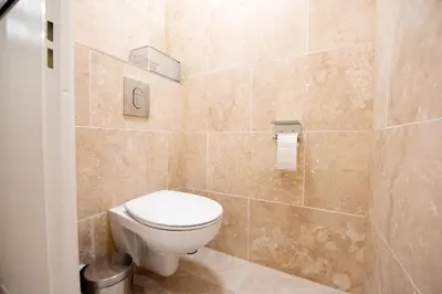 a bathroom with a toilet and a tiled wall at Sunny Palazzio T3 Old Port, Beaches, Congress in Cannes
