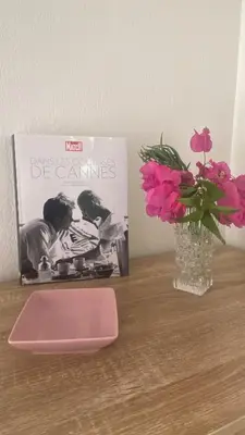 a vase with pink flowers and a book on a table at une pépite ZEN et COSY, parking jardin, idéal pour se ressourcer au calme in Le Cannet
