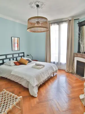 a bedroom with a large bed and a wooden floor at Les Bananiers centre ville Cannes in Cannes