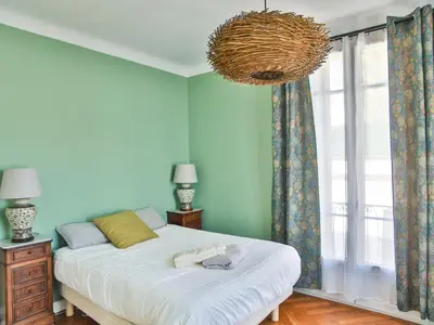 a bedroom with a bed and a large window at Les Bananiers centre ville Cannes in Cannes