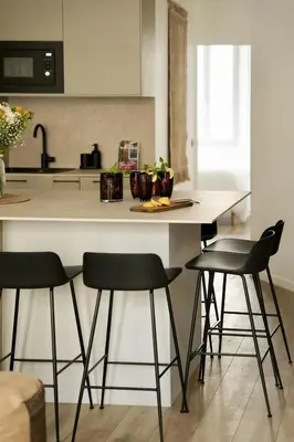 a kitchen with a white counter with four bar stools at Somptueux avec grande terrasse in Cannes