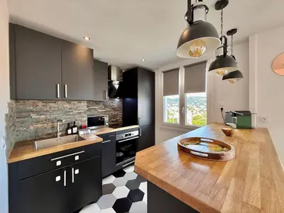 a kitchen with black cabinets and a wooden counter top at T3 Sea view walking distance of Palais, AC , Parking, Terrace in Cannes
