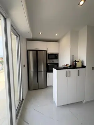 a kitchen with white cabinets and a stainless steel refrigerator at Cannes 2 suites 2 terrasses in Cannes