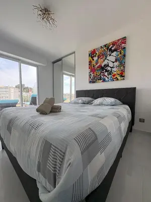 a bedroom with a large bed with a painting on the wall at Cannes 2 suites 2 terrasses in Cannes