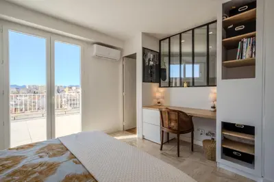 a bedroom with a bed and a desk and a window at Appartement avec Terrasse et Vue Mer in Cannes