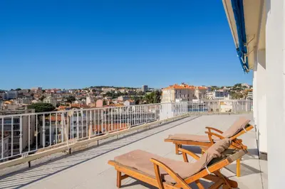 a balcony with chairs and a view of a city at Appartement avec Terrasse et Vue Mer in Cannes