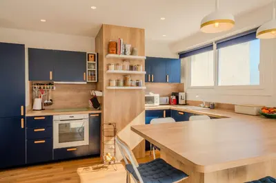 a kitchen with blue cabinets and a wooden table at Appartement avec Terrasse et Vue Mer in Cannes