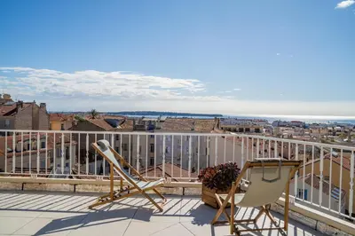 a balcony with chairs and a view of the city at Appartement avec Terrasse et Vue Mer in Cannes