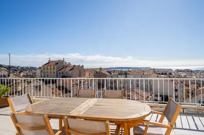 a wooden table and chairs on a balcony at Appartement avec Terrasse et Vue Mer in Cannes