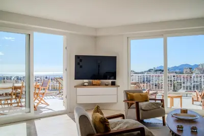 a living room with a tv and sliding glass doors at Appartement avec Terrasse et Vue Mer in Cannes