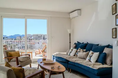a living room with a blue couch and a table at Appartement avec Terrasse et Vue Mer in Cannes