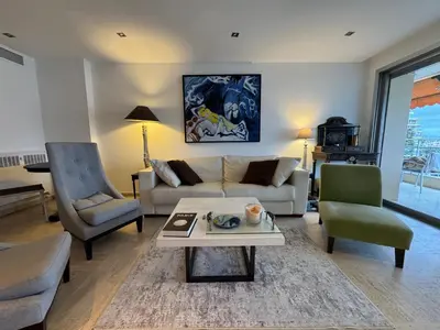 a living room with a couch and a table and chairs at 90 m2 Palm Beach apartment with 2 balconies Very stylish and central in Cannes