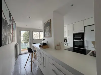 a kitchen with white cabinets and a black appliance at 90 m2 Palm Beach apartment with 2 balconies Very stylish and central in Cannes