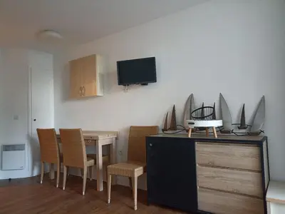 a dining room with a table and chairs and a tv at Appartement 4 personnes ,résidence vue mer et jardin, piscine, parking in Cannes