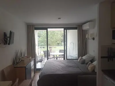 a bedroom with a bed and a balcony with a table at Appartement 4 personnes ,résidence vue mer et jardin, piscine, parking in Cannes