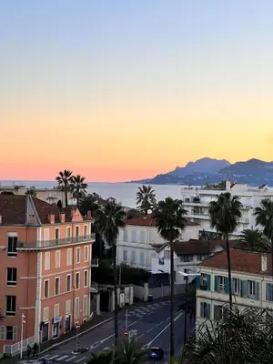 a view of a city at sunset with palm trees at Luxury Appartment with terrace and side sea view in Cannes