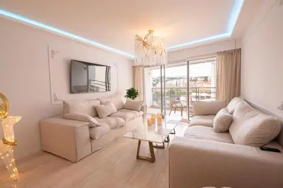 a living room with white furniture and a large window at 2-bedroom luxurious apartment with balcony and parking in Cannes