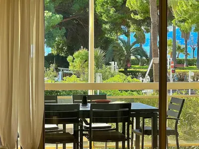 a dining room with a table and chairs and a window at Luxurious 2-bedroom Pointe Croisette, Sea view, private parking in Cannes