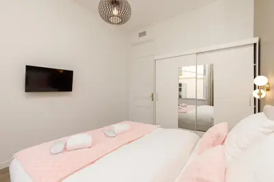 a white bedroom with a bed and a tv at Modern 3 bedroom apartment ideally located in Cannes