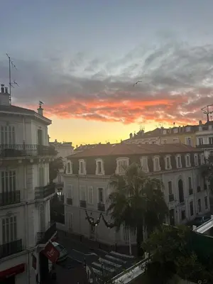 a sunset in a city with buildings and palm trees at Cannes Centre Mimosas 1 chambre Salon in Cannes