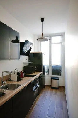a kitchen with black cabinets and a wooden floor at 2 Pieces bourgeois centre de Cannes 4 couchages une pépite in Cannes