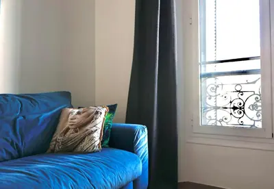 a blue couch with a pillow on it next to a window at 2 Pieces bourgeois centre de Cannes 4 couchages une pépite in Cannes