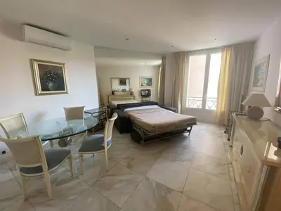 a living room with a bed and a glass table at 540 Cannes La Croisette - Joli studio au calme coté jardin in Cannes