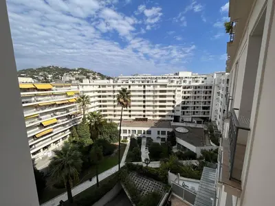 a view of a large white building with palm trees at 540 Cannes La Croisette - Joli studio au calme coté jardin in Cannes