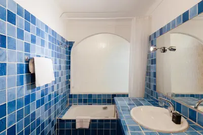 a blue tiled bathroom with a sink and a tub at Una Rosa Blu YourHostHelper in Cannes