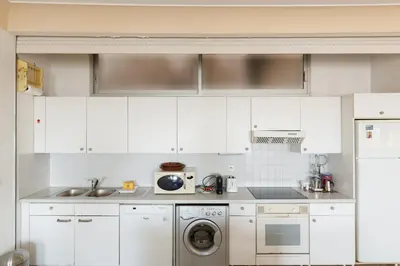 a kitchen with white cabinets and a washer and dryer at Una Rosa Blu YourHostHelper in Cannes