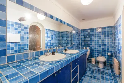 a blue tiled bathroom with two sinks and a toilet at Una Rosa Blu YourHostHelper in Cannes